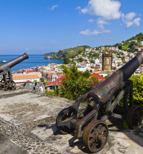 "Two cannons located on Fort George are pointed to St. George's, the capital city of Grenada. Built by the French in 1650, this beautiful city, facing a horseshoe-shaped harbor called The Carenage, is surrounded by a hillside of an old volcano crater. The French also built Fort George in 1705 on the promontory overlooking the city. Although most of the building is currently used by the police, visitors can stroll in the fortress and enjoy the breathtaking panorama over the city and harbor."